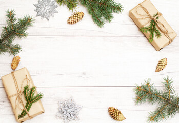 Merry Christmas frame and wallpaper. Happy New Year composition. Christmas gift, pine cones, fir branches on wooden white background.