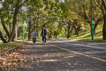 Happy woman riding on an e-scooter with her son. Young and beautiful caucasian woman rides electric scooter with boy in park.