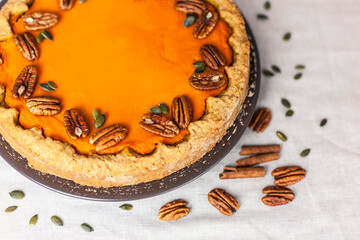 Pumpkin homemade pie on a gray linen background with top view of food ingredients for decoration