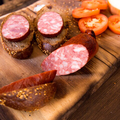 Sausage slices and sandwiches on a wooden Board,with slices of tomatoes,onions with slices of bread,still life