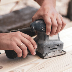 A carpenter works with a tool. Close-up of hands and woodworking tools.