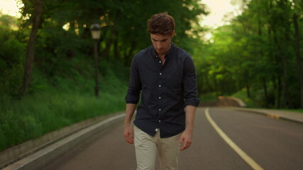 Obraz premium Disappointed guy going outside on road. Serious man having walk outdoors