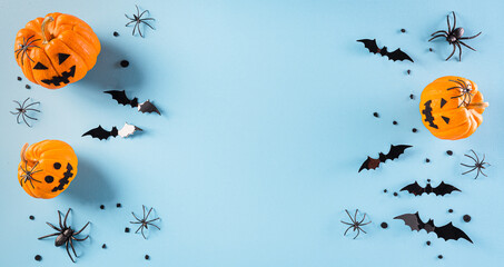 Halloween decorations made from pumpkin, paper bats and black spider on pastel blue background....