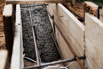 Timber formwork with metal reinforcement for pouring concrete and creating a solid foundation for a building or fence. Construction process