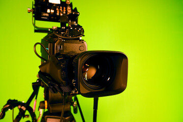 TV video camera on the background of a green chroma key. Camcorder lens in television studio. TV...