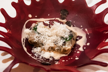 Shrimp ravioli with cheese on a red plate