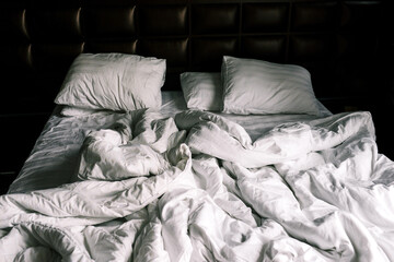 Unmade double empty bed with white linens. Sheets and pillows in the apartment or hotel after a...
