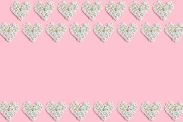 the floral concept in pastel colors. frame made hearts of white hydrangea flowers on a pink background. Valentine's day layout. space for text, top view