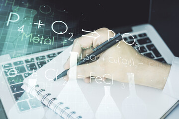 Creative chemistry concept with hand writing in notebook on background with laptop. Multiexposure