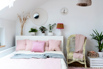 Bright interior of bedroom in the attic with double bed, pink pillows and wooden floor. Scandinavian design and relax in hotel. 