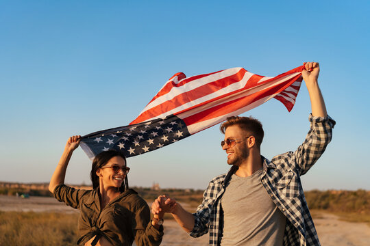 Happy couple holding hands together while strolling with american flag