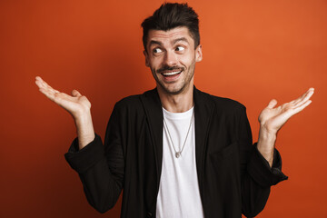 Photo of young happy man posing at camera with arms aside