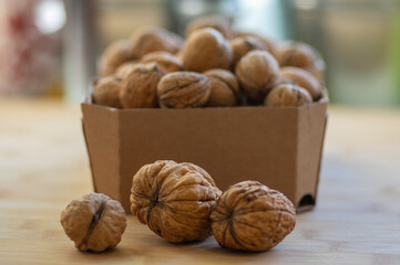 Walnuts on table in hard shells, group of dry ripened fruits in cardboard boxes, crop food ingredients ready for cooking