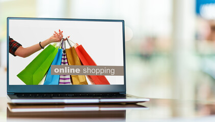 Paper shopping bags on laptop computer screen. Shopping online.
