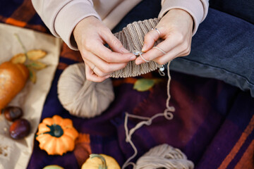 girl knitting with beige threads in the park on a picnic