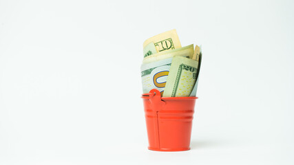 Small red bucket full of money on white background © Artem Sudoplatov