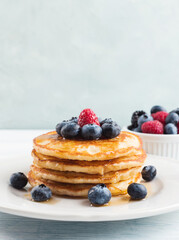 Stack of pancakes with fresh blueberries served in a dish with maple syrup. Delicious breakfast