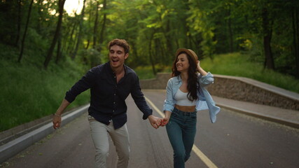 Beautiful girl and guy jumping in park. Young couple having fun outside