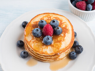 Stack of pancakes with fresh blueberries served in a dish with maple syrup. Delicious breakfast