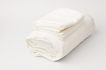 Stack of clean bed sheets on white  background, closeup.