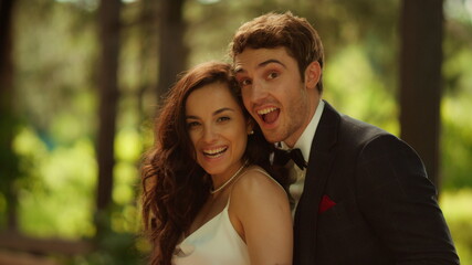 Positive bride and groom posing on wedding. Couple showing rings in park