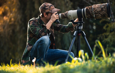 wildlife photographer using telephoto lens with camouflage coating photographing wild life using...