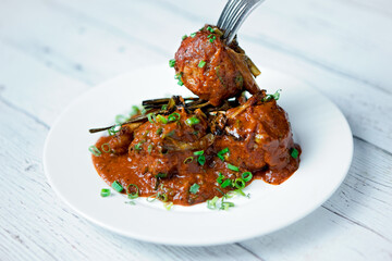 Fork picking one meatball from the plate