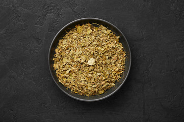 Dry Kasuri Methi or Fenugreek in black bowl on dark slate table top. Dried Fenugreek is is the popular seasoning of many asian cuisines.