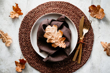 Top view of decorated table setting dish with fallen leaf. Thanksgiving or Autumn festive dinner concept.