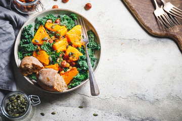 Top view of season salad with grilled pumpkin, kale, chickpea, pepitas and nuts. Autumn vegetarian healthy recipe.