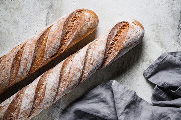 Top view of two brown baguettes on a concrete background.