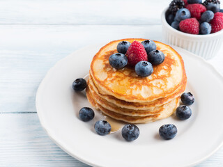 Stack of pancakes with fresh blueberries served in a dish with maple syrup. Delicious breakfast