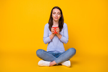 Portrait of her she nice attractive pretty dreamy calm cheery girl sitting lotus position enjoying drinking cacao isolated bright vivid shine vibrant yellow color background