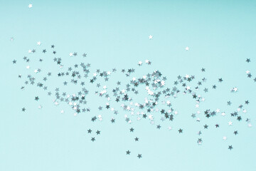 Silver stars shine on a bright light blue background. Festive holiday bright background.