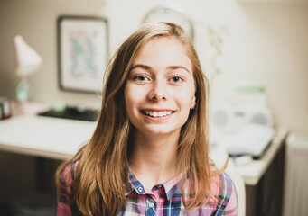 Portrait of blond long haired happy smiling caucasian teenage girl in her room