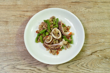 spicy fried chili squid with chop pork and basil leaf couple slice yard long bean on plate