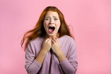 Frightened and screaming woman shocked isolated over pink background. Stressed and depressed pretty girl because of bad news.