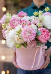Bouquet in box. Gift box with beautiful flower. Woman holding big beautiful blossoming box bouquet of fresh roses, lilac, ranunculus, eustoma and others.