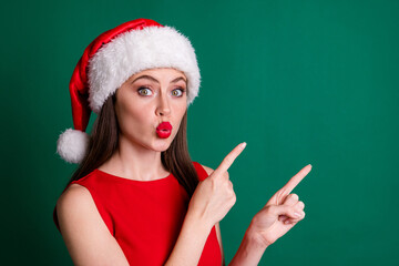 Closeup photo of attractive lady meet customers newyear decor shop store send air kisses direct fingers empty space wear santa cap red dress snow girl costume isolated green color background