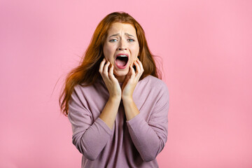 Frightened and screaming woman shocked isolated over pink background. Stressed and depressed pretty girl because of bad news.