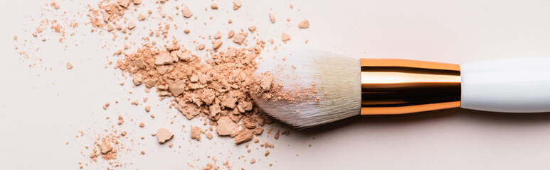 close up view of cosmetic brush with face powder on beige background, panoramic shot