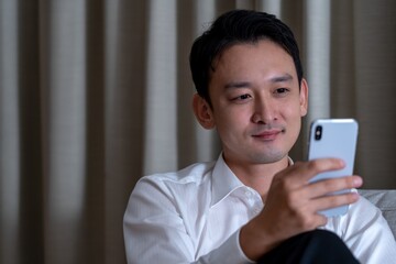 携帯を操作するアジア人男性