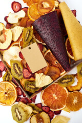 Scattered dried fruits and fruit pastille in open craft paper box