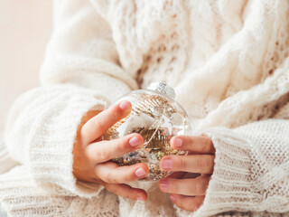 Kid with decorative balls for Christmas tree.Boy in cable-knit oversized sweater.Cozy outfit for snuggle weather.Transparent balls with red, golden spangles inside.Winter holiday spirit.New year.