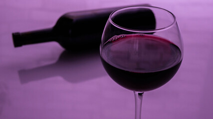  A glass of red wine with a bottle on a pink background
