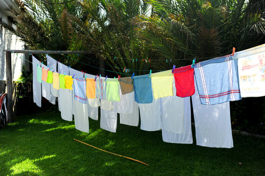 Toallas blancas y trapos de cocina de colores sec&aacute;ndose al sol en un tendedero al aire libre
