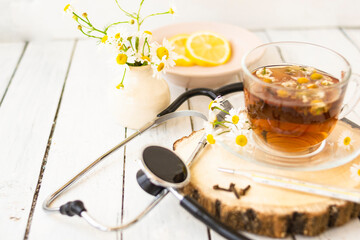 Decoction of chamomile, dried flower in flower tea and a phonendoscope, sliced lemon on a white...