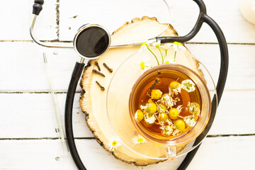 Decoction of chamomile, dried flower in flower tea and a phonendoscope, sliced lemon on a white...