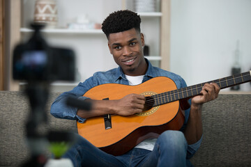 musician playing a guitar before a recording camera