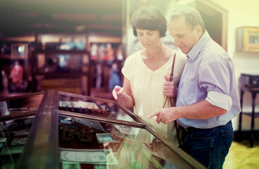 middle aged men and women collector evaluates the exhibition in historical museum